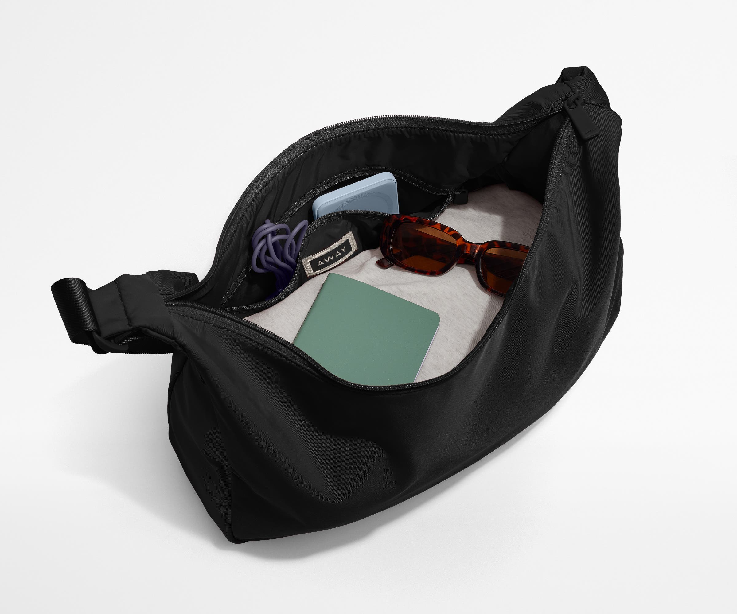 Featherlight crossbody packed with a sweater, notebook, sunglasses, and portable charger