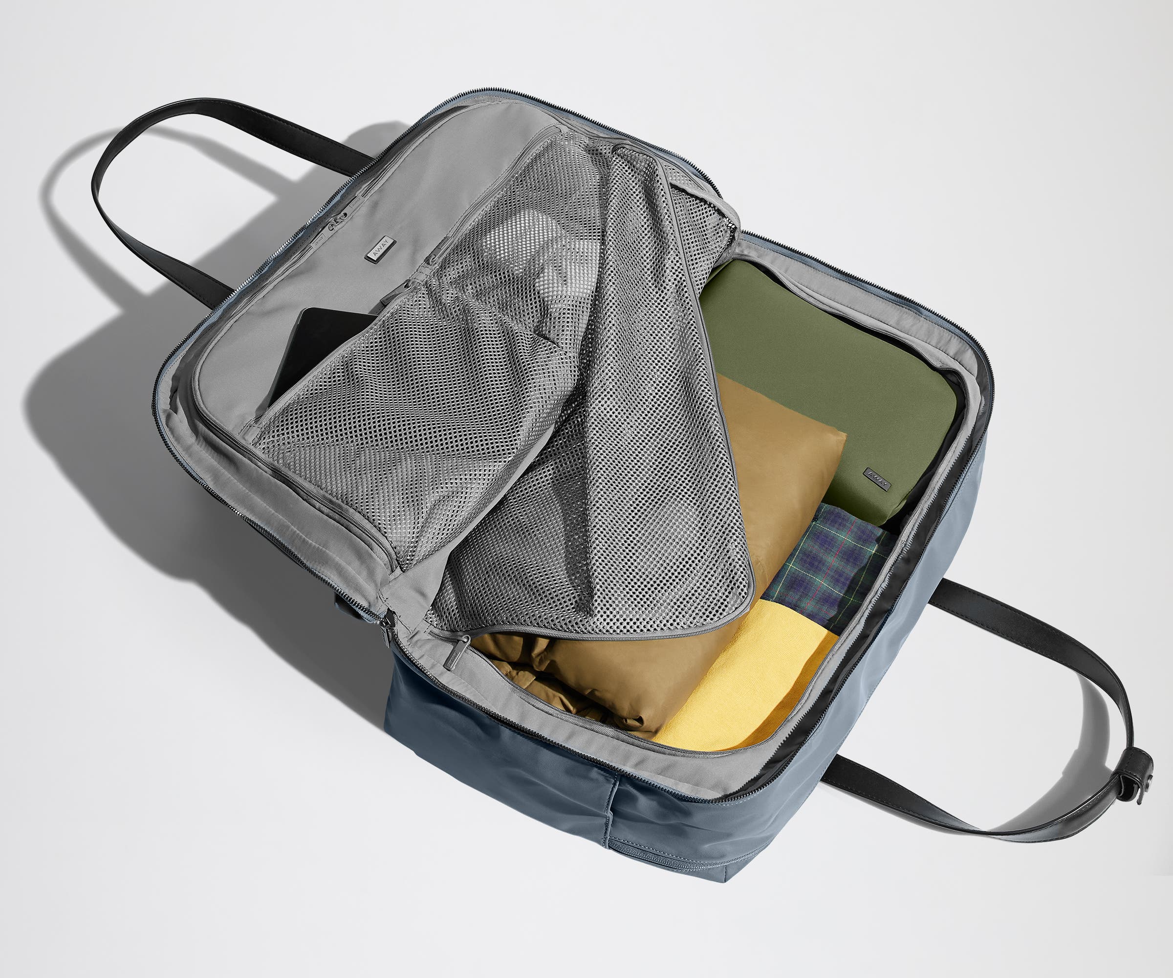 Open clamshell Weekender bag packed with travel essentials, including clothes and Small Toiletry Bag