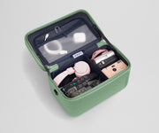 Train case packed with tech gear including multiple cameras, headphones, charging cords, and earpods