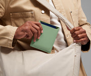 Person packing the Passport Wallet in the Featherlight Crossbody bag