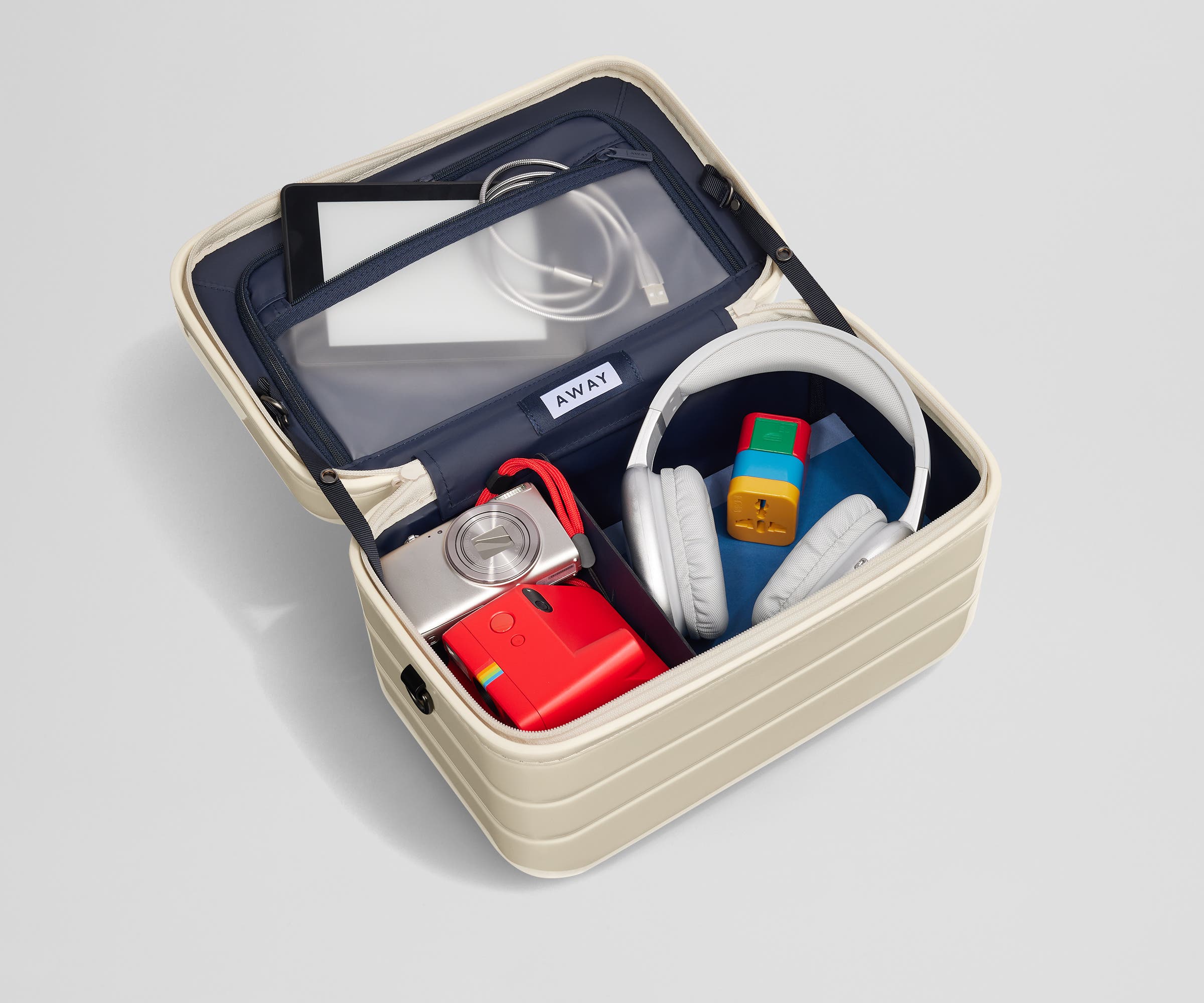 Train Case packed with tech including an e-reader, charging cords, cameras, and headphones