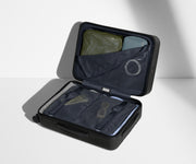 The Carry-On suitcase in Jet Black shown open on its side and packed with Away's packing organizers to show capacity and the interior compression system, designed to help you pack more in