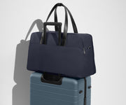 Weekender sitting on an Away Large suitcase, using the trolley sleeve pass-through
