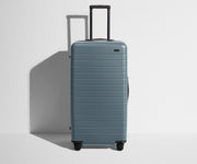 Front product view of The Trunk suitcase in Coast Blue with raised handle