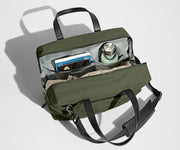 Main compartment packed with a light sweater, notebook, tablet, and water bottle. The detachable shoulder strap is clipped onto the bag.