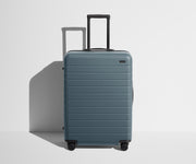 Front product view of The Medium suitcase in Coast Blue with raised handle