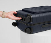 The Front Pocket Carry-On suitcase in Navy Blue shown from below highlighting the underside grab handle