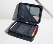 The Medium Flex suitcase in Navy Blue shown open on its side and packed with Away's packing organizers to show capacity and the interior compression system, designed to help you pack more in