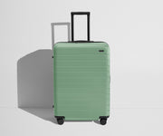 Front product view of The Medium Flex suitcase in Sea Green with raised handle