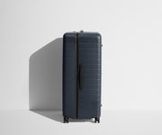 Side product view of The Trunk suitcase in Navy Blue to show the slimmer top lid and deeper main compartment for easy access and packing