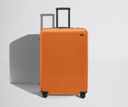Front product view of The Large Flex suitcase in Sorbet Orange with raised handle