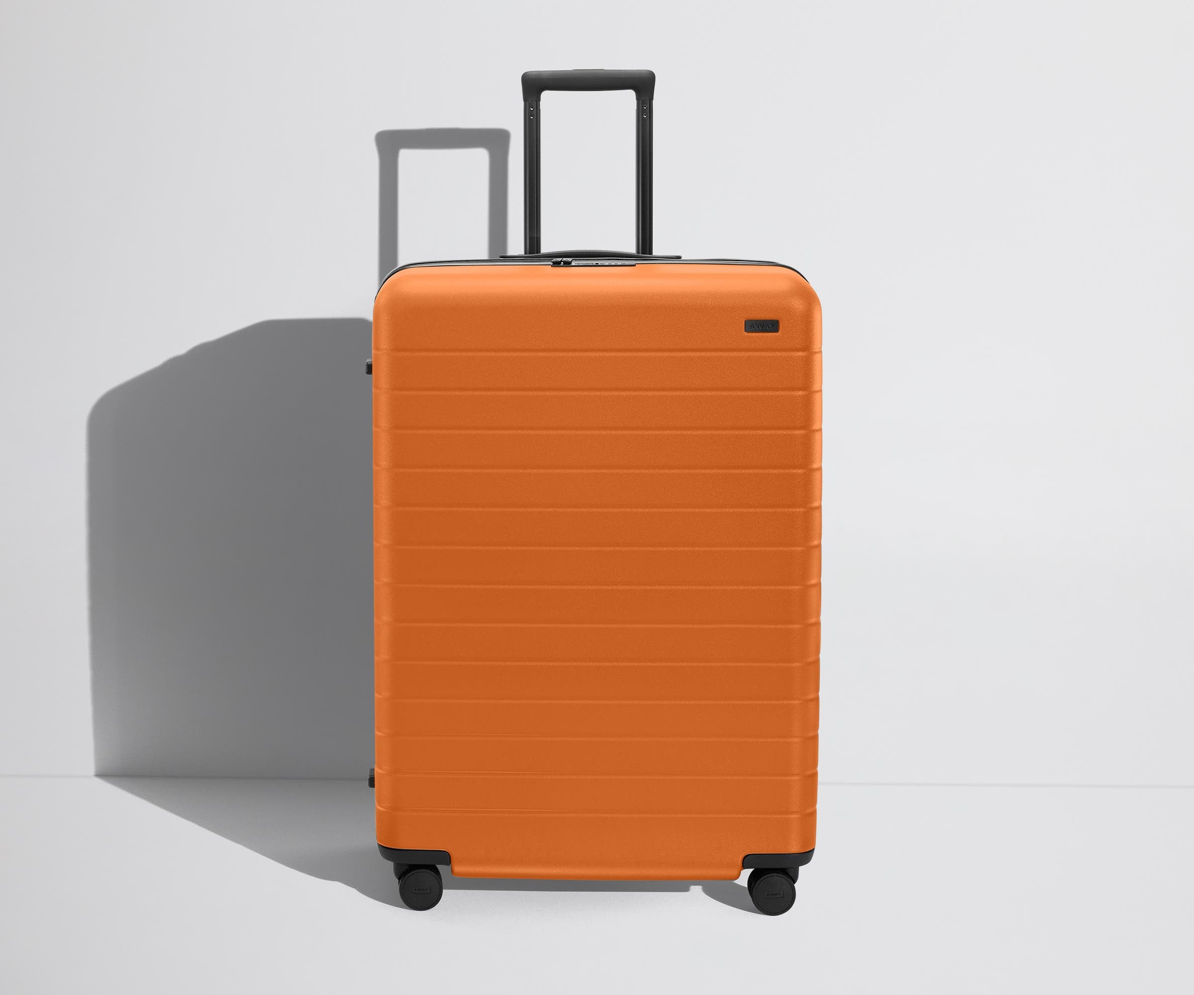 Front product view of The Large Flex suitcase in Sorbet Orange with raised handle