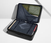The Large Flex suitcase in Jet Black shown open on its side and packed with Away's packing organizers to show capacity and the interior compression system, designed to help you pack more in
