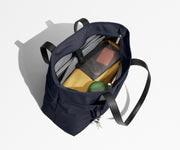 Tote bag packed with a laptop, water bottle, travel pouch, and sweater. A key is attached to the hidden key leash