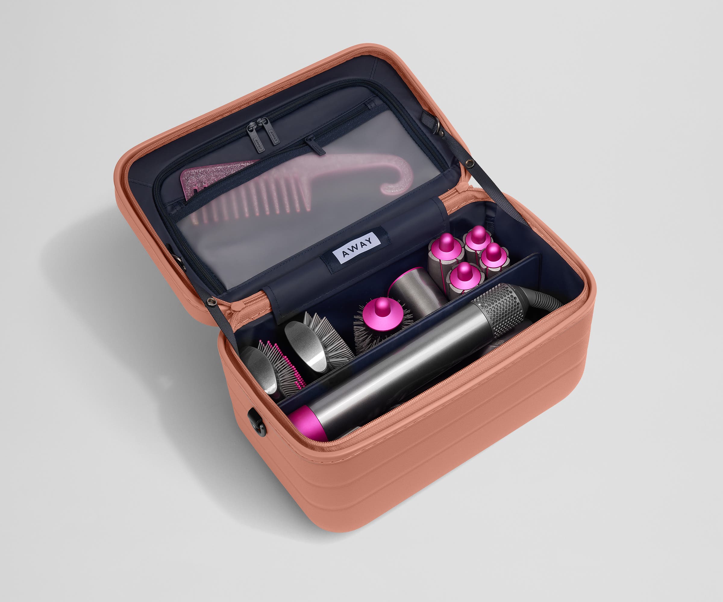 Train case packed with hair tools including a blow dryer and its attachments and a Brush