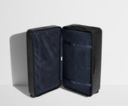The Trunk suitcase in Jet Black shown open in an upright position to show interior organization and compression system