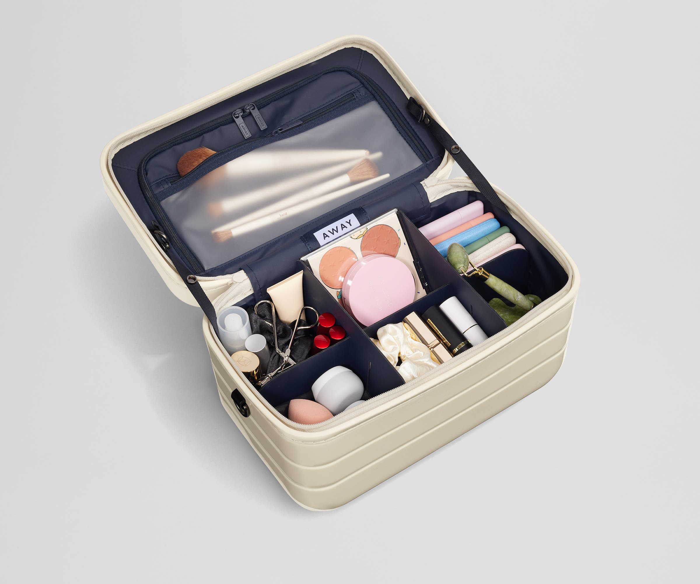 Train case packed with makeup essentials including brushes and sponges, lipstick, and other makeup