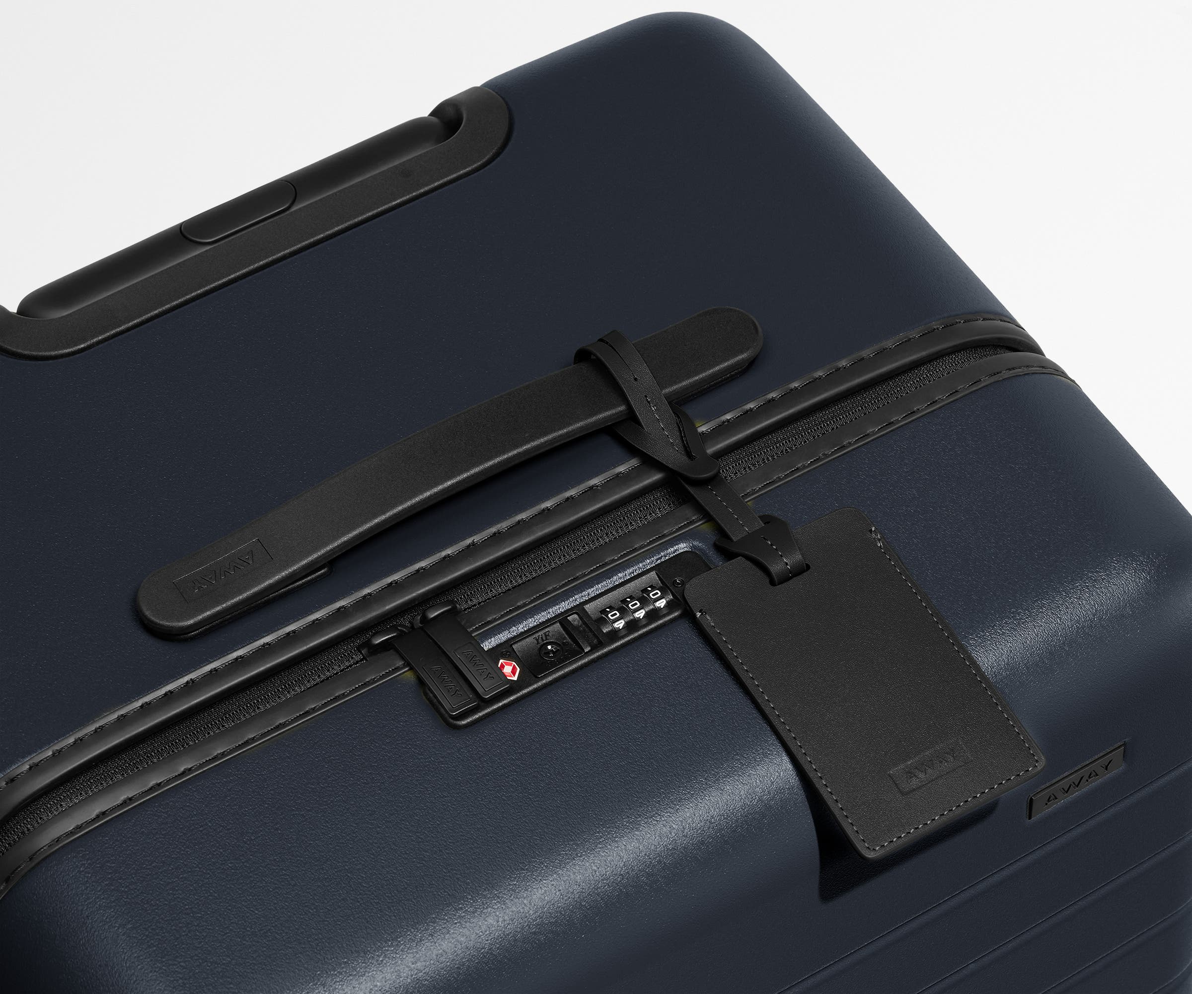 The Trunk suitcase in Navy Blue shown shown from above highlighting TSA-approved combination lock and recycled leather luggage tag