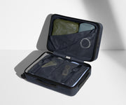 The Carry-On suitcase in Navy Blue shown open on its side and packed with Away's packing organizers to show capacity and the interior compression system, designed to help you pack more in