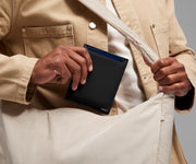 Person packing the Passport Wallet in the Featherlight Crossbody bag