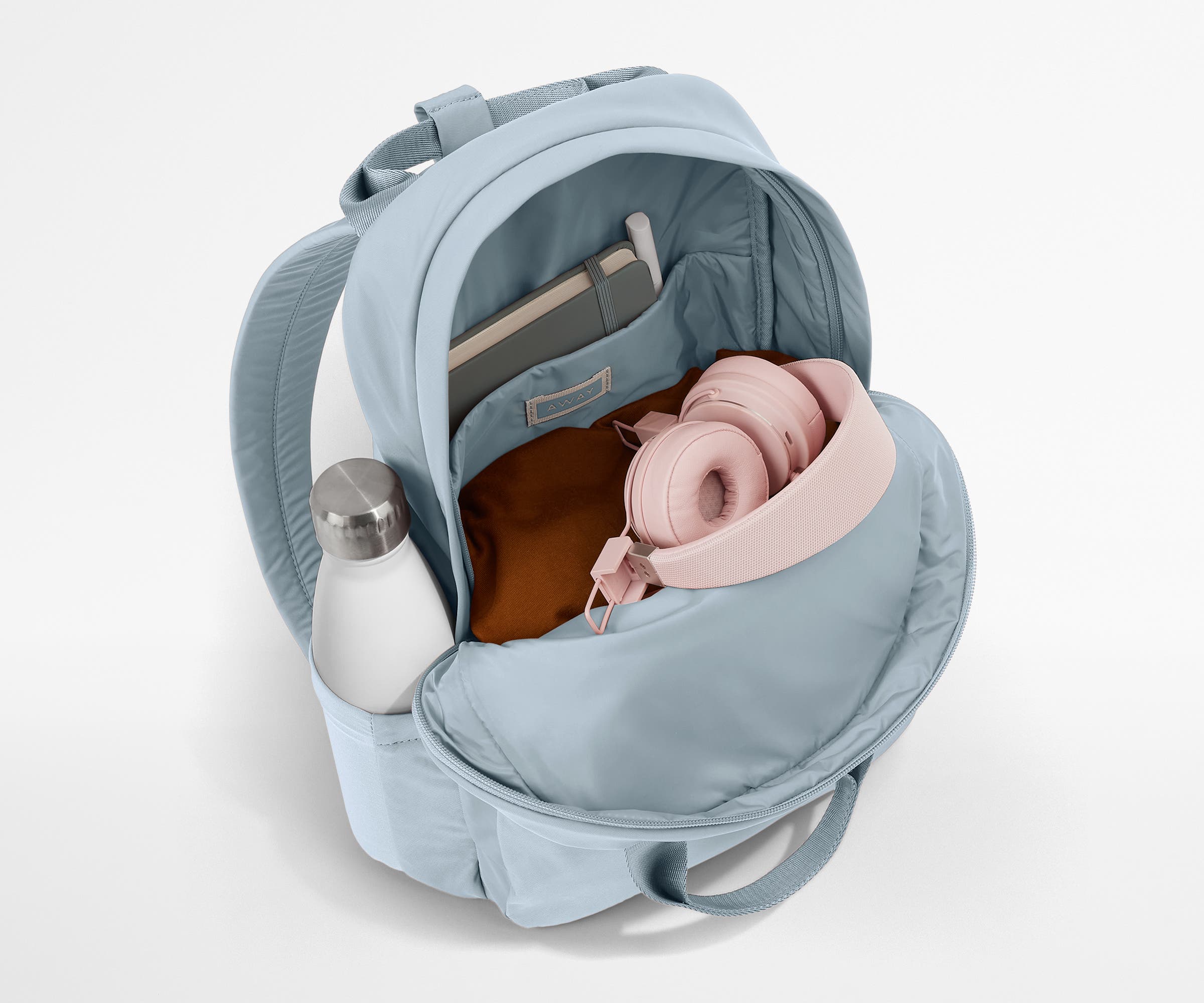 Featherlight Backpack packed with a sweater, notebook, headphones, and water bottle