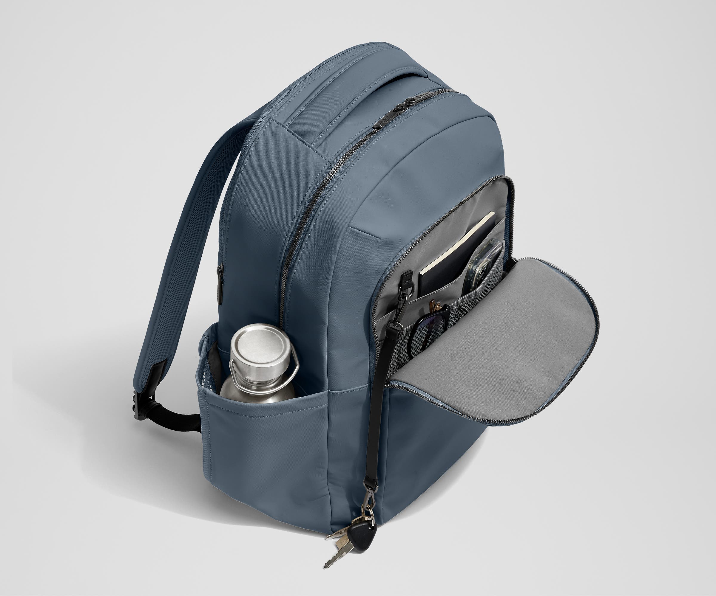Front exterior zip pocket, detachable key clip, and exterior water bottle pocket of The Commuter Backpack