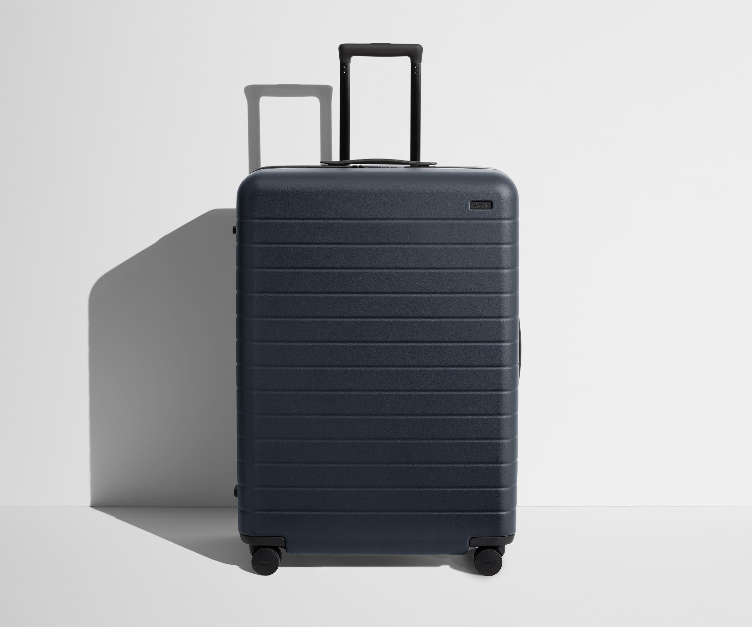 Front product view of The Large suitcase in Navy Blue with raised handle