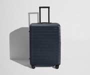 Front product view of The Medium Flex suitcase in Navy Blue with raised handle