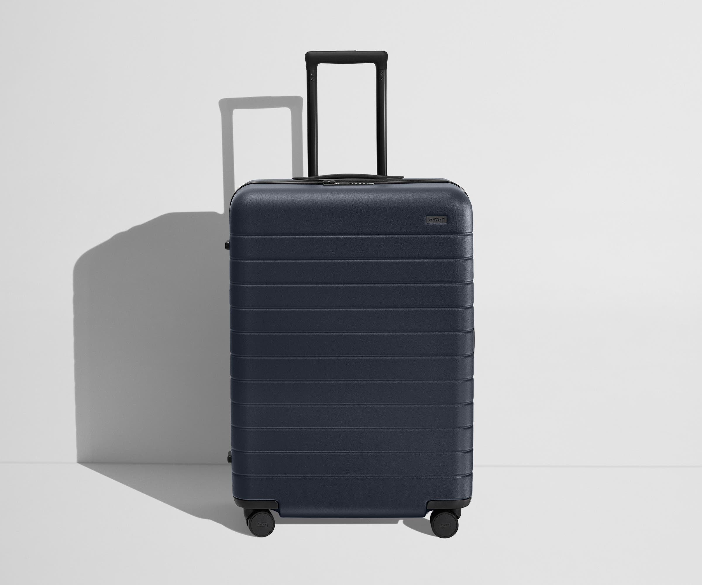Front product view of The Medium Flex suitcase in Navy Blue with raised handle