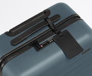 The Carry-On suitcase in Coast Blue shown shown from above highlighting TSA-approved combination lock and recycled leather luggage tag