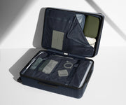 The Medium suitcase in Navy Blue shown open on its side and packed with Away's packing organizers to show capacity and the interior compression system, designed to help you pack more in
