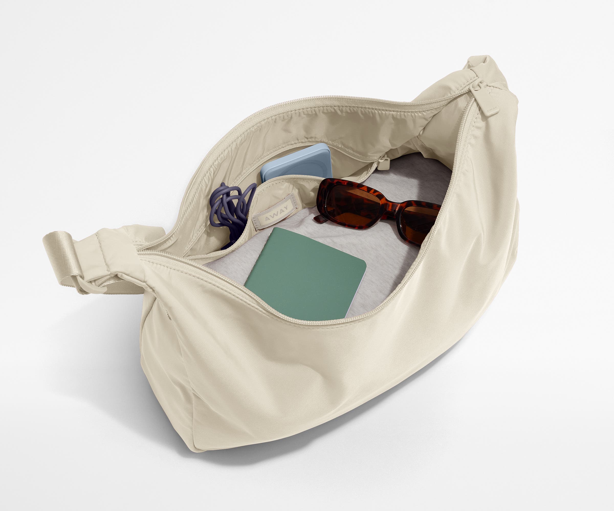 Featherlight crossbody packed with a sweater, notebook, sunglasses, and portable charger