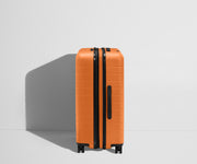 Side product view of The Medium Flex suitcase in Sorbet Orange shown fully expanded