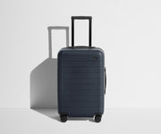 Front product view of The Carry-On suitcase in Navy Blue with raised handle