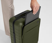 Zoomed in shot of talent slipping a laptop into the front pocket of The Front Pocket Carry-On in Olive Green