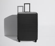 Front product view of The Large Flex suitcase in Jet Black with raised handle