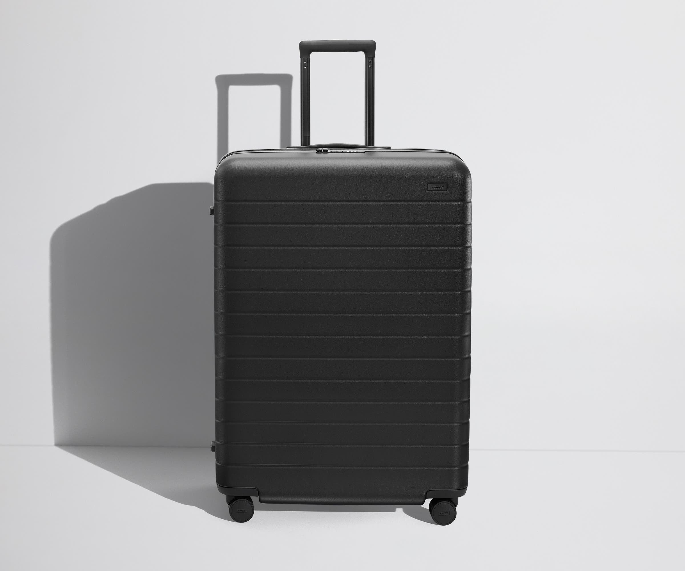 Front product view of The Large Flex suitcase in Jet Black with raised handle