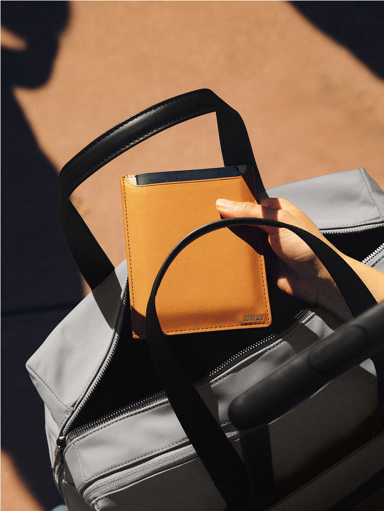 Leather passport holder packed into an Away duffle bag