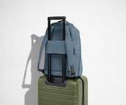 The Everywhere Zip Backpack in Coast Blue sitting on an Away Carry-On suitcase