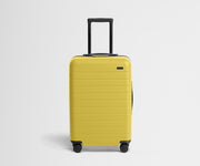 Front product view of The Bigger Carry-On suitcase in Sunshine Yellow with raised handle