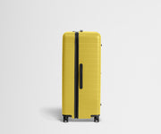 Side product view of The Trunk suitcase in Sunshine Yellow to show the slimmer top lid and deeper main compartment for easy access and packing