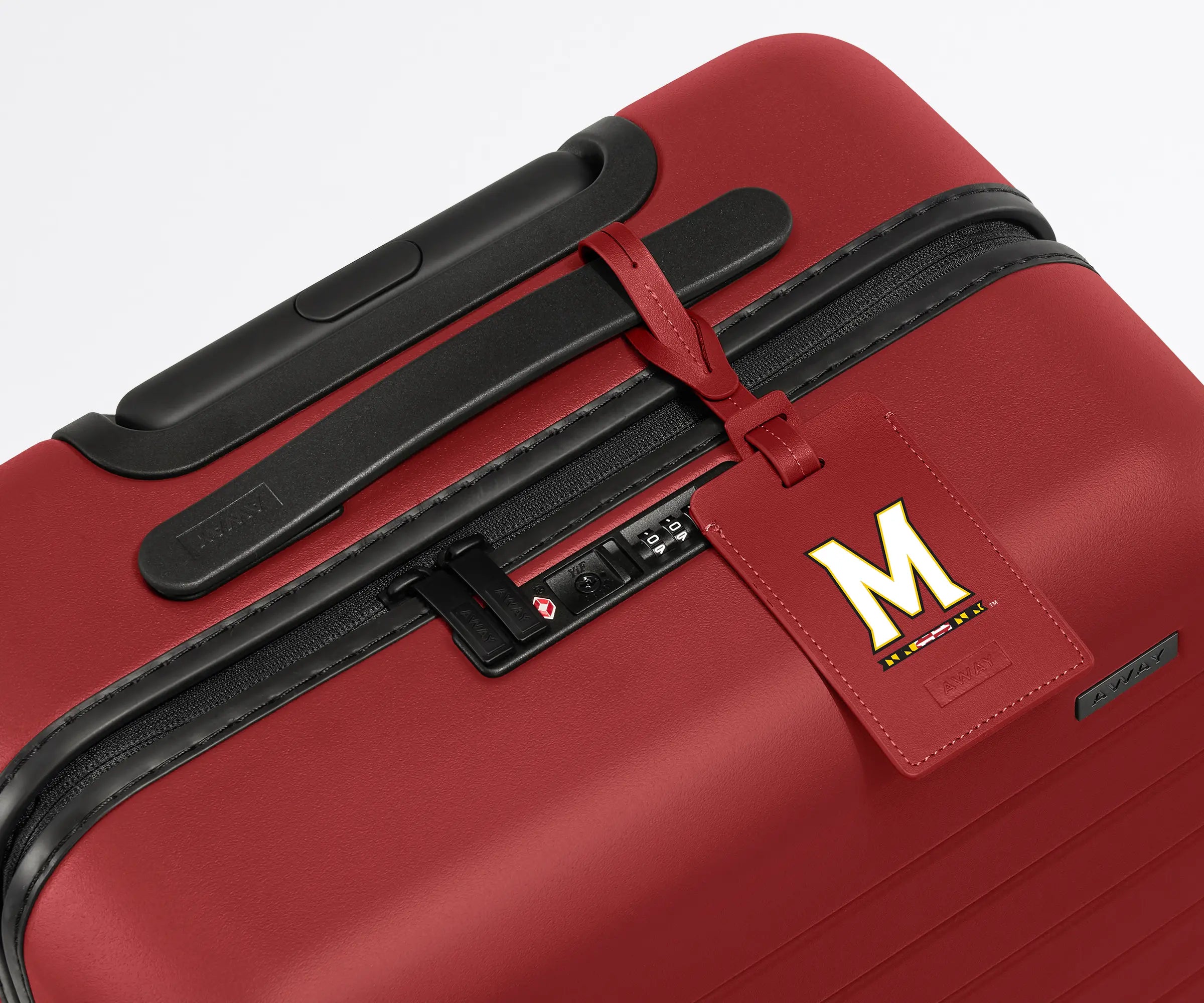 Red luggage tag with the University of Maryland logo on it attached to a red hardside suitcase.