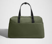 Green duffel bag with black straps on a light gray background