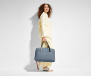 5'9" person carrying The Overnight Bag by its leather handles