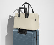 The Overnight Bag secured to an Away checked suitcase using the trolley sleeve