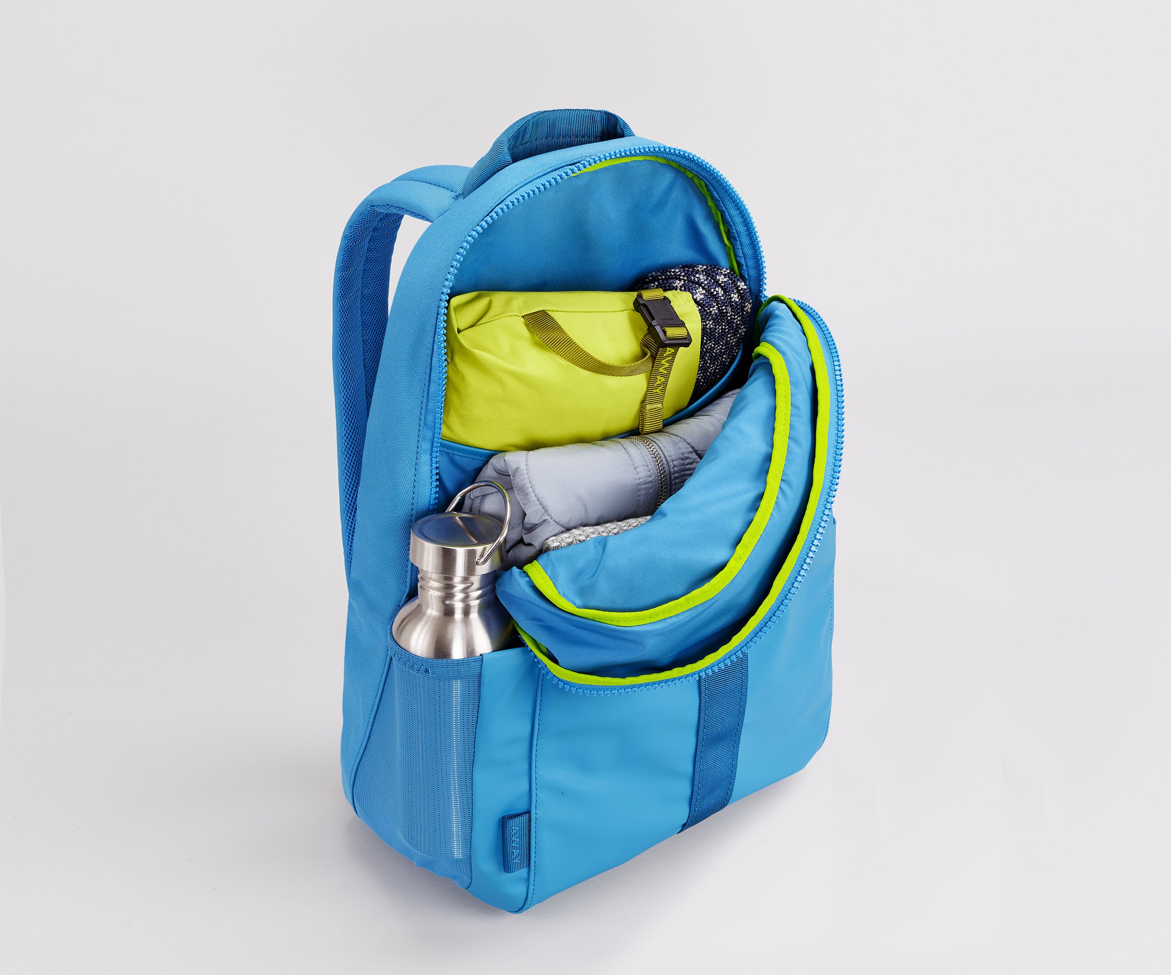 Main compartment packed with an organizational pouch, notebook, and headphones. Water bottle in the exterior water bottle pocket