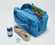 Active Duffle 55L packed with travel essentials and outdoor gear including a packing cube, sunglasses, wallet, carabiner and rope, and water bottle