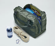 Active Duffle 55L packed with travel essentials and outdoor gear including a packing cube, sunglasses, wallet, carabiner and rope, and water bottle