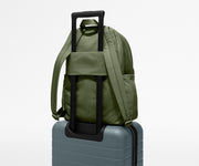 Green backpack with rolling handle on a gray suitcase against a light gray background
