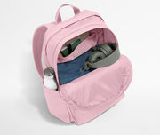 Pink backpack with a water bottle, denim item, and gray strap on a light gray background
